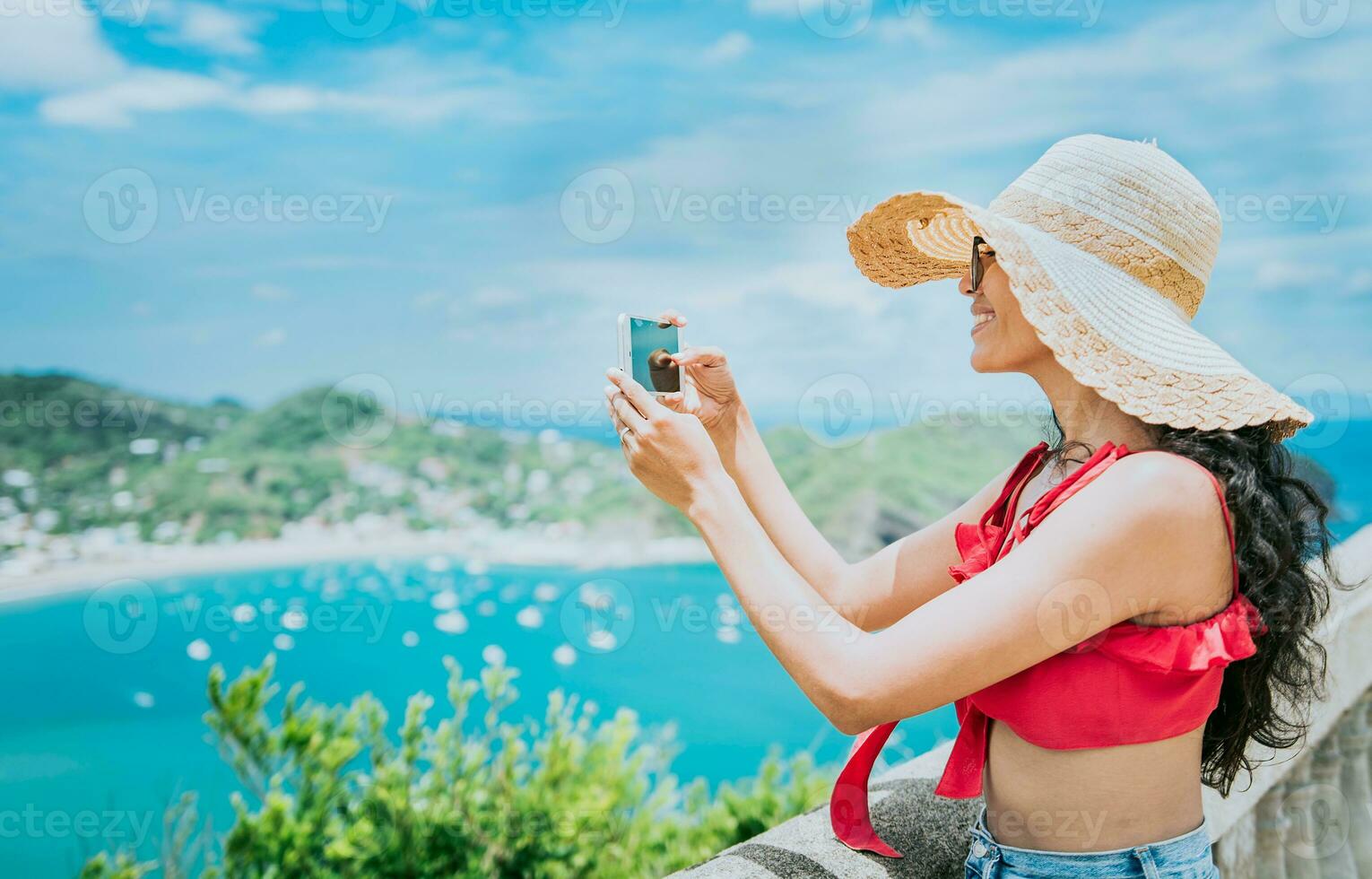Traveler girl photographing a bay from a viewpoint. Happy tourist woman in a hat photographing a viewpoint, Travel and tourism promotion concept photo