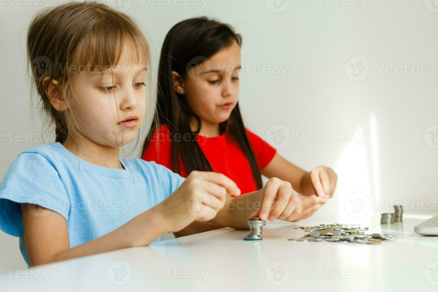 portrait of little girls sitting at table and calculating money photo