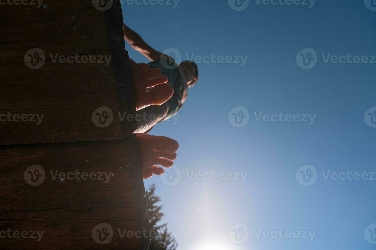 a person standing on a wooden platform with their feet in the air photo