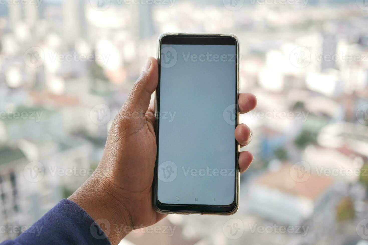 young man using smart phone with empty screen against city background photo