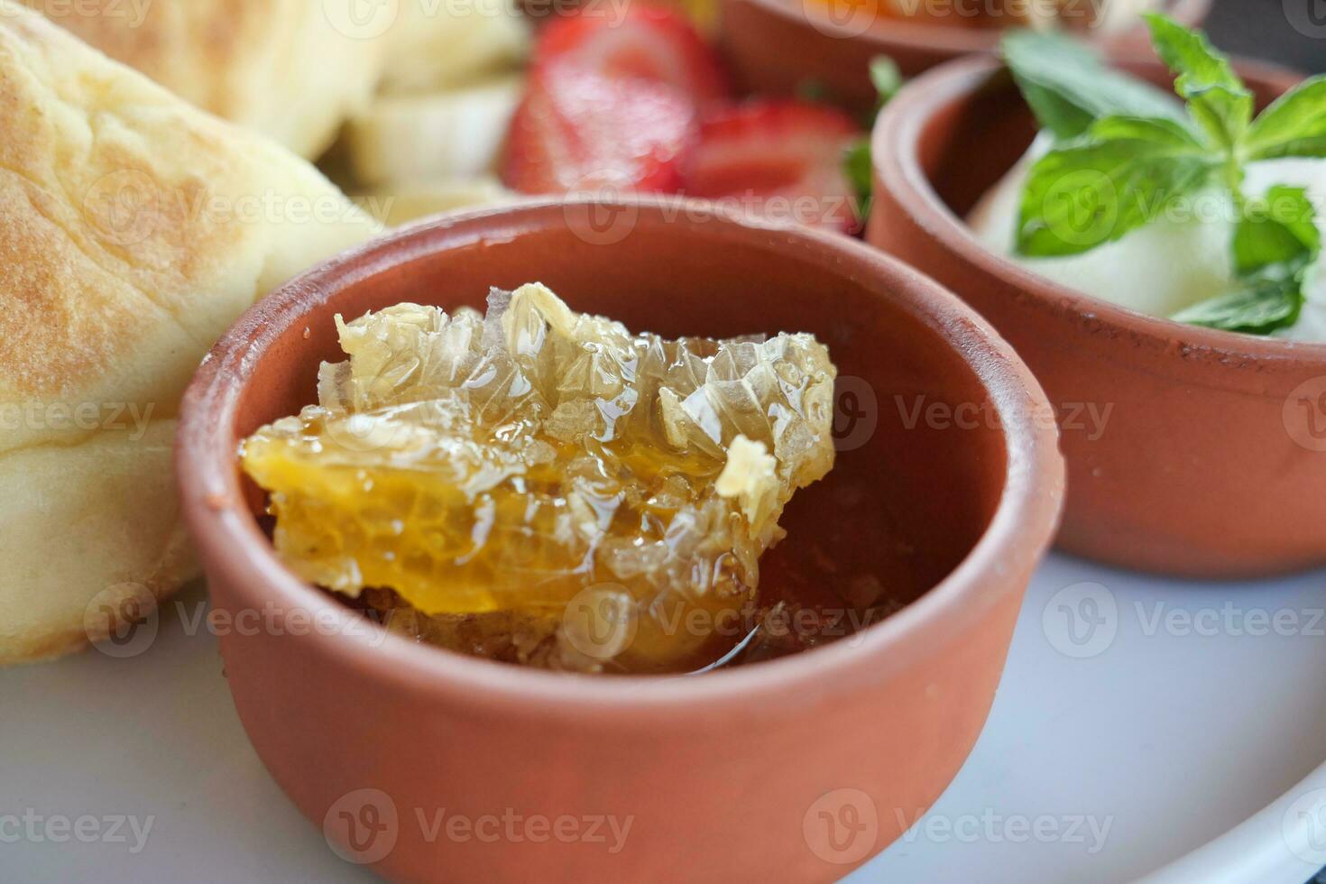close up of fresh honey with comp in a jar served with bread and strawberry photo