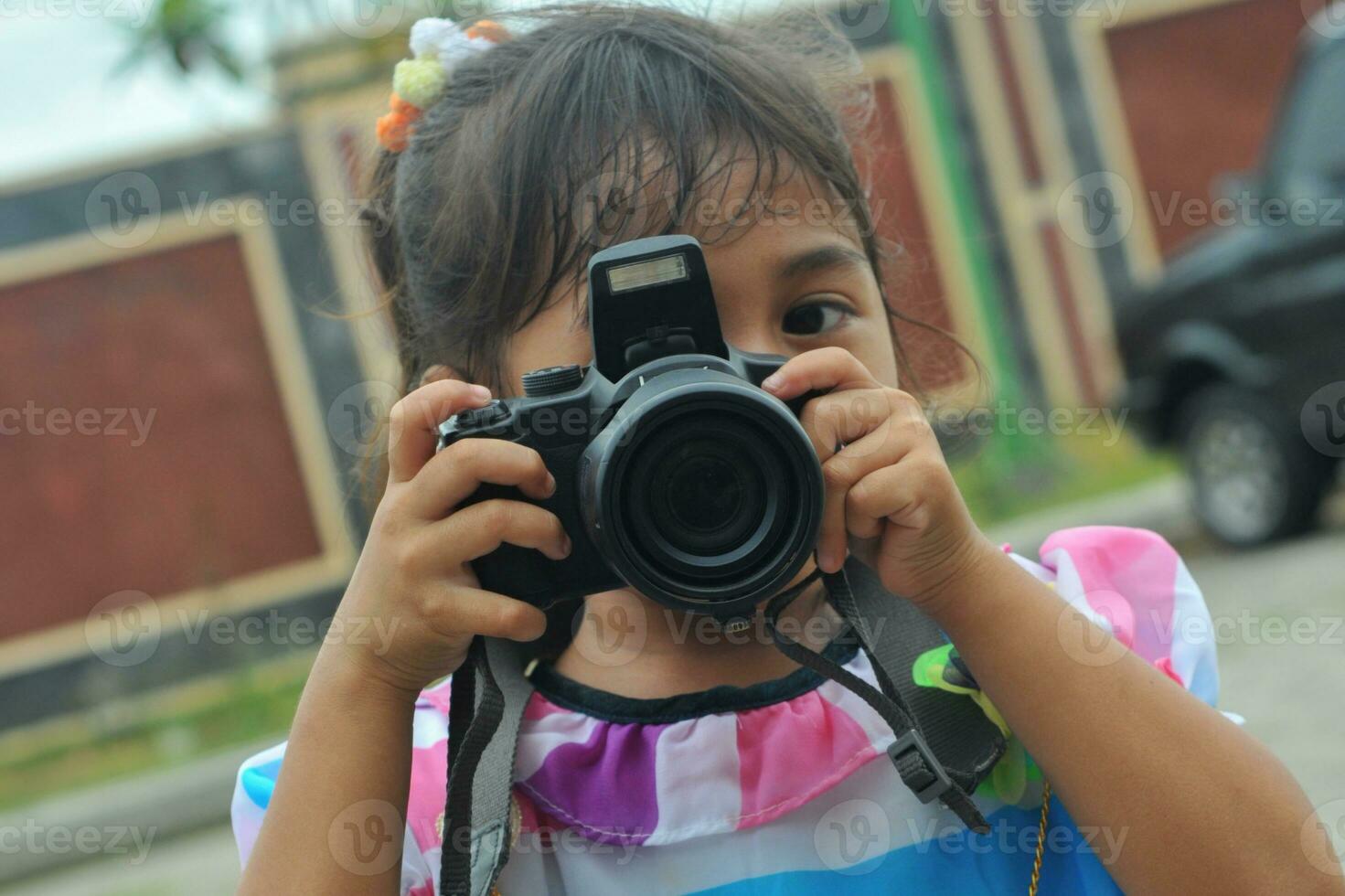 little girl is holding a digital camera photo
