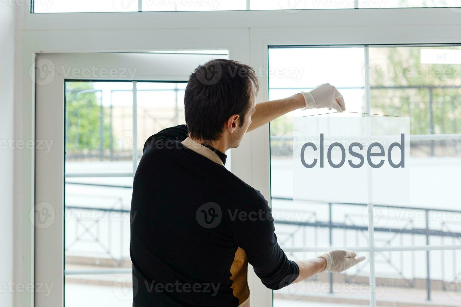Portrait of a waiter showing open sign at the coffee shop photo