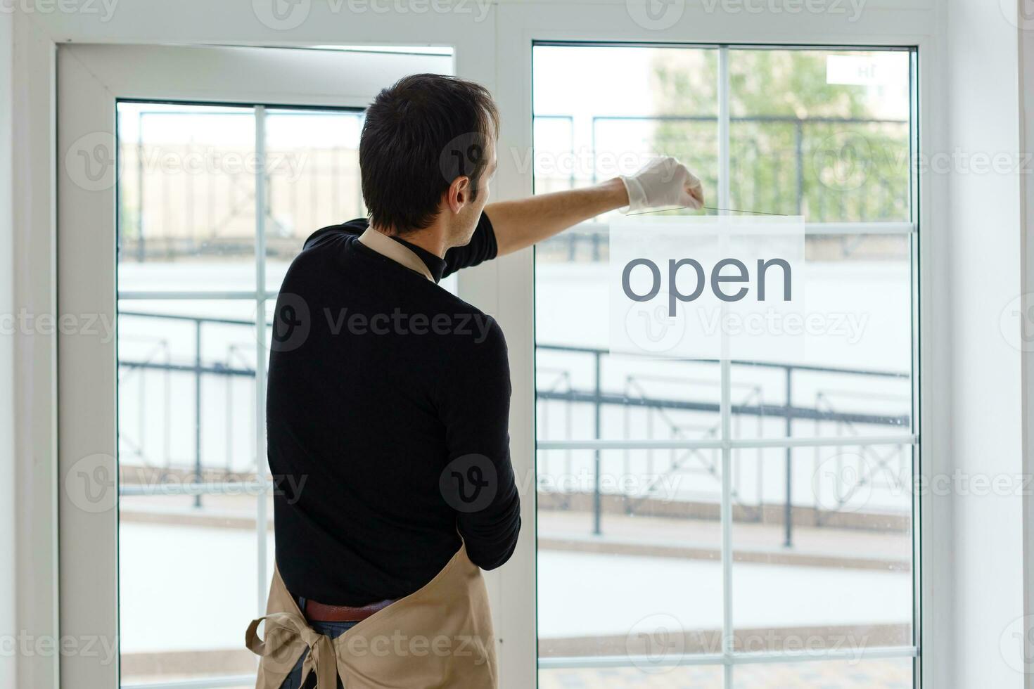 Portrait of a waiter showing open sign at the coffee shop photo