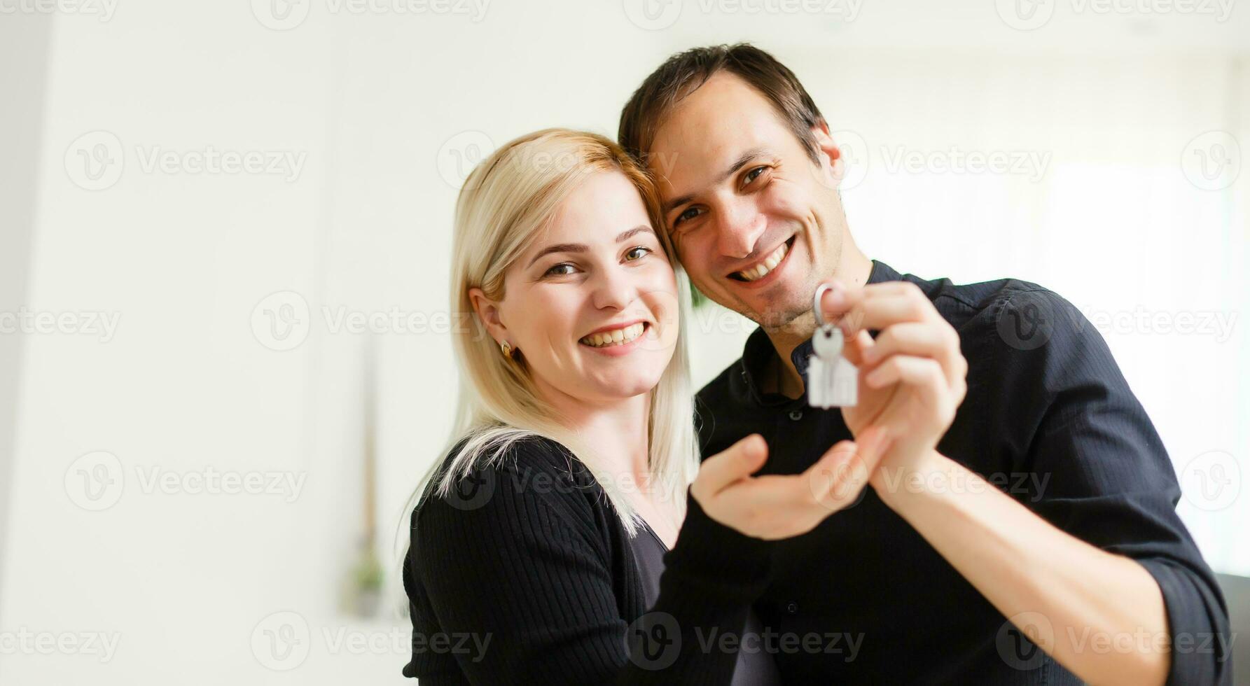 Happy smiling young couple showing a pair of keys of their new house photo