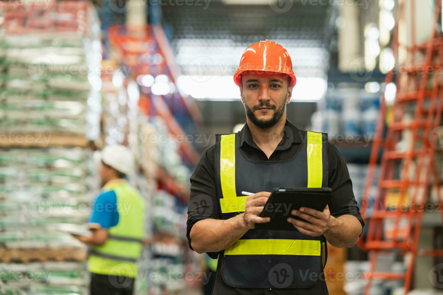 Professional manager man employee smile using tablet check stock working at warehouse. Worker wearing high visibility clothing and a hard hat, helmet and checking and count up goods boxes delivery. photo
