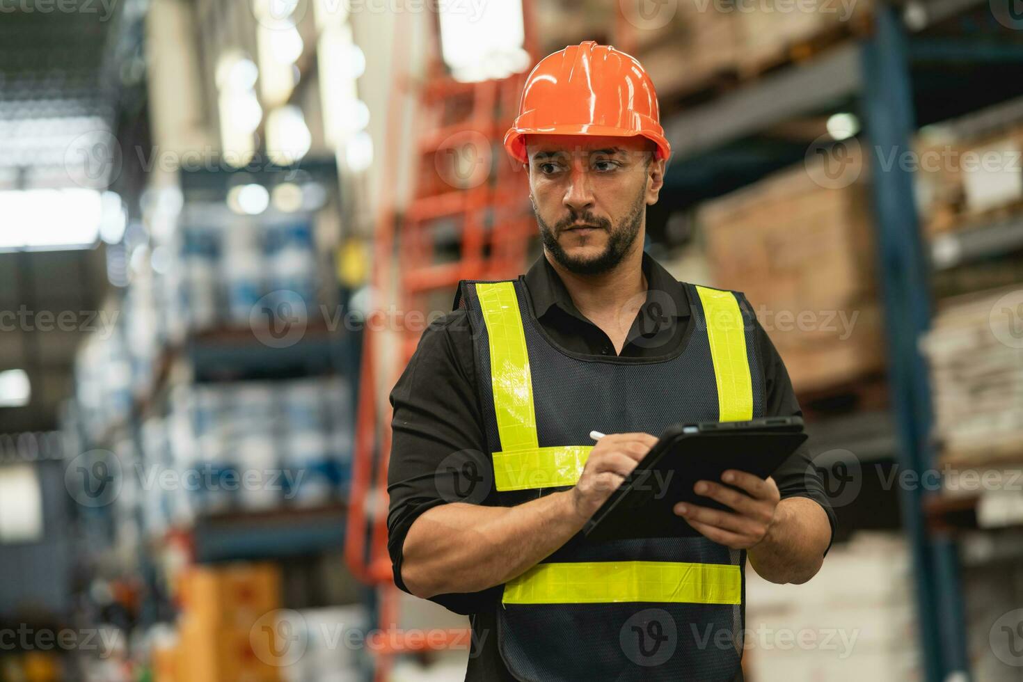 Professional manager man employee using tablet check stock working at warehouse. Worker wearing high visibility clothing and a hard hat, helmet and checking and count up goods or boxes for delivery. photo