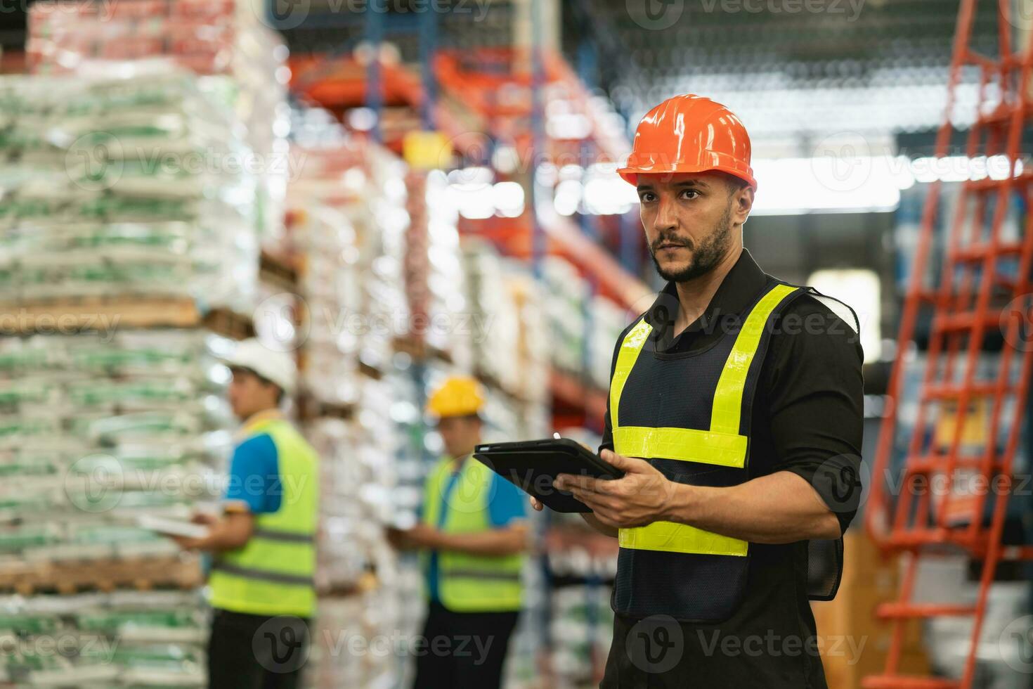 Professional manager man employee using tablet check stock working at warehouse. Worker wearing high visibility clothing and a hard hat, helmet and checking and count up goods or boxes for delivery. photo