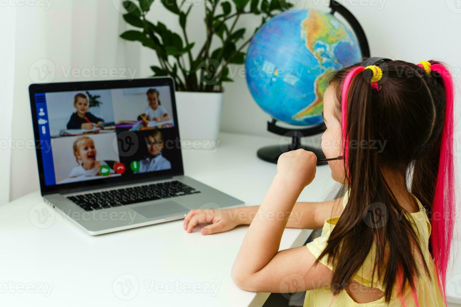 Cool online school. Kid studying online at home using a laptop. Cheerful young little girl using laptop computer studying through online e-learning system. Distance or remote learning photo