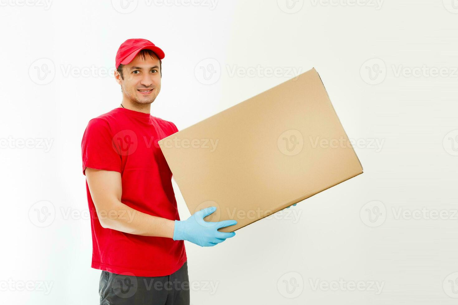 Smiling young delivery man holding and carrying a cardbox isolated on white background photo