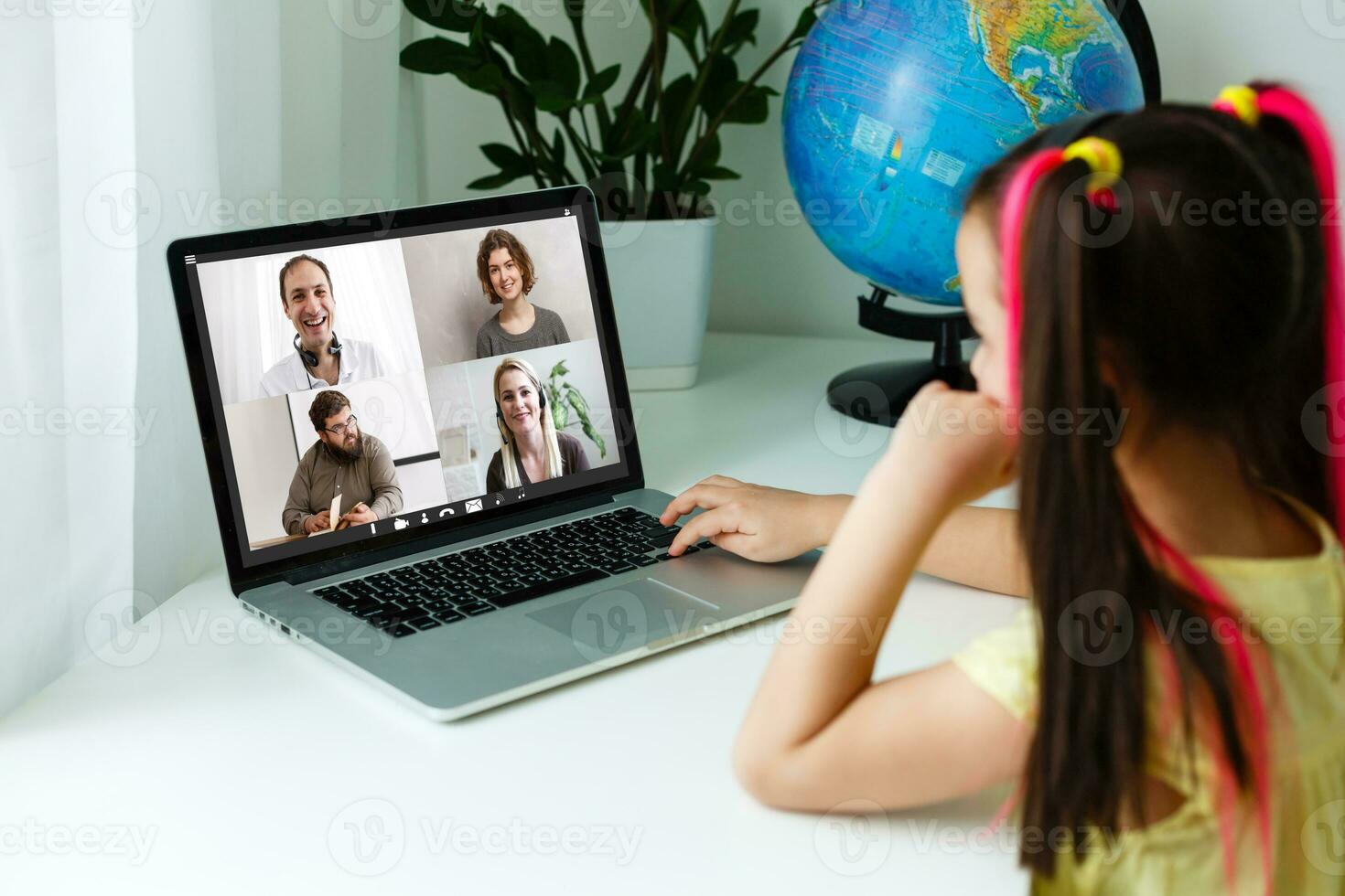 Cool online school. Kid studying online at home using a laptop. Cheerful young little girl using laptop computer studying through online e-learning system. Distance or remote learning photo