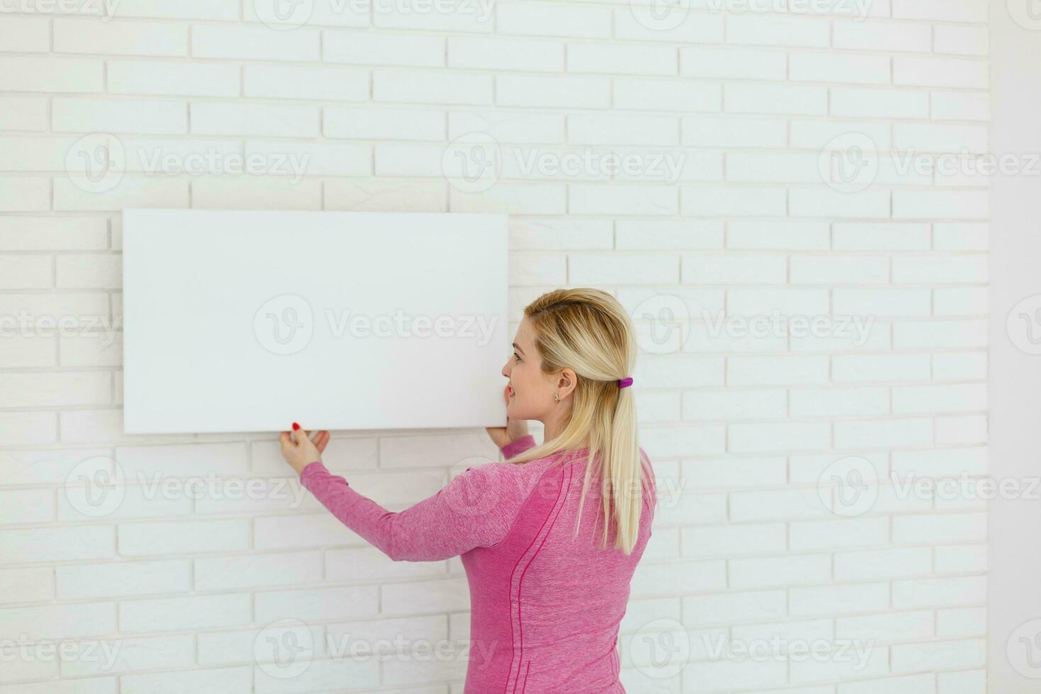 Photo of woman looking at the blank white canvas. Horizontal, mockup