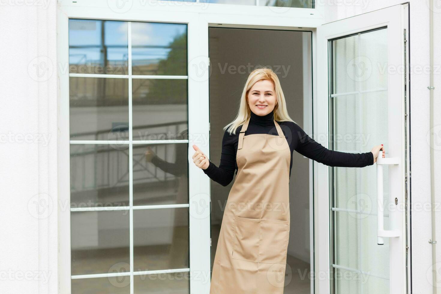 Half length portrait of waitress dressed in apron with copy space for brand name open store starting work ready to serve visitors, woman entrepreneur barista standing at restaurant entrance photo