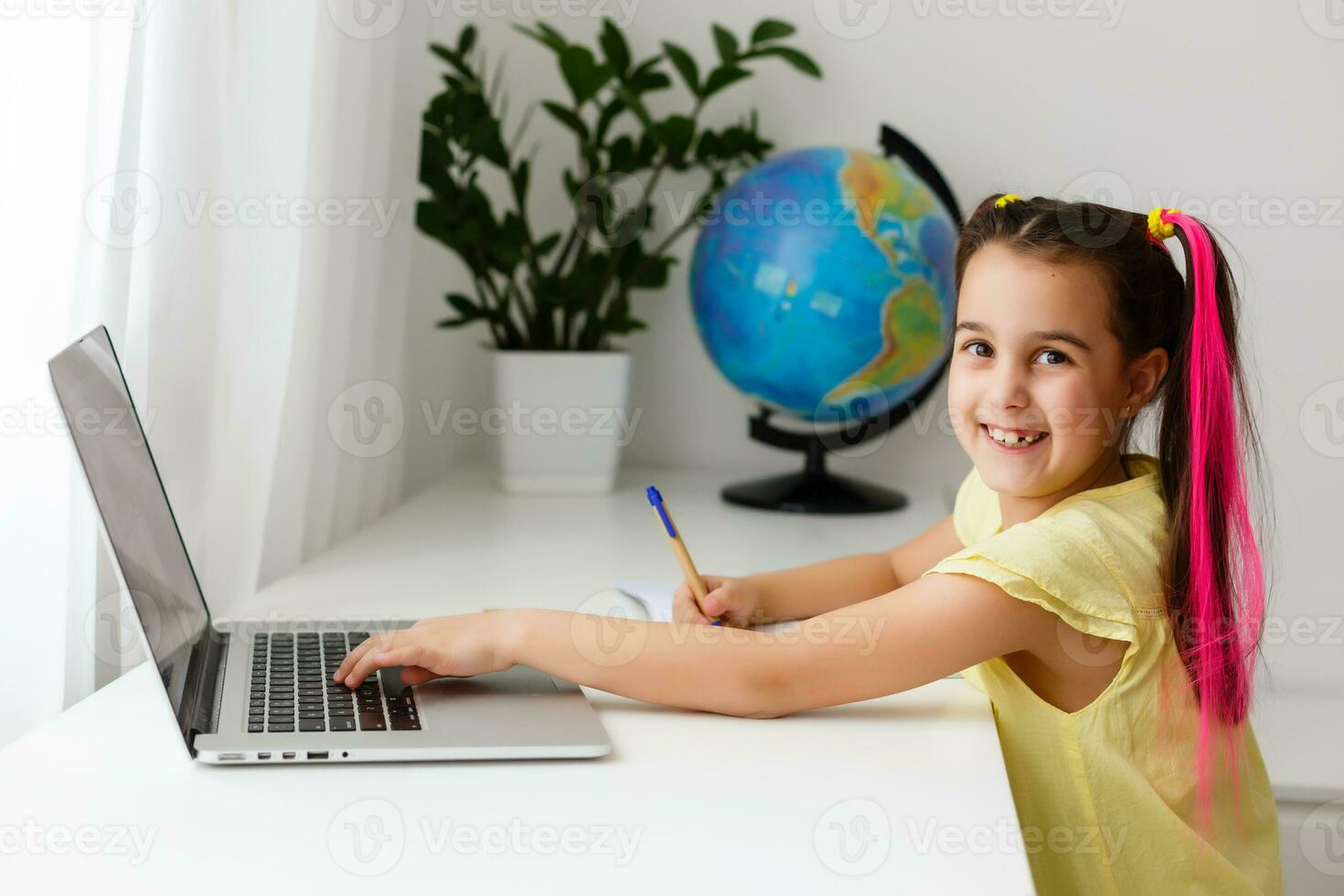 Cool online school. Kid studying online at home using a laptop. Cheerful young little girl using laptop computer studying through online e-learning system. Distance or remote learning photo
