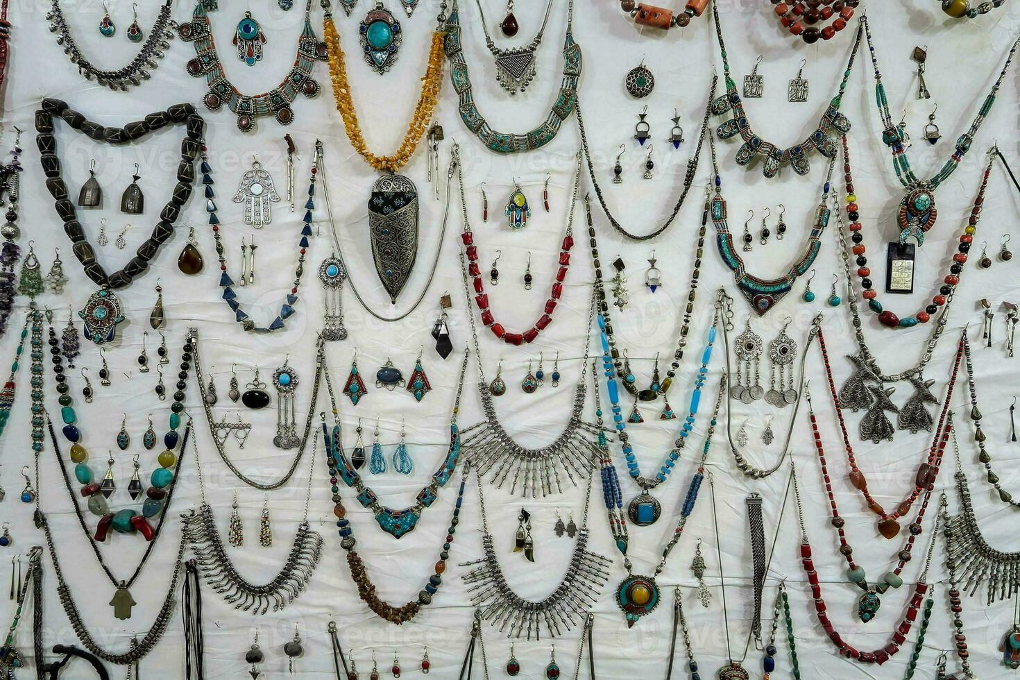 many different types of necklaces are displayed on a wall photo