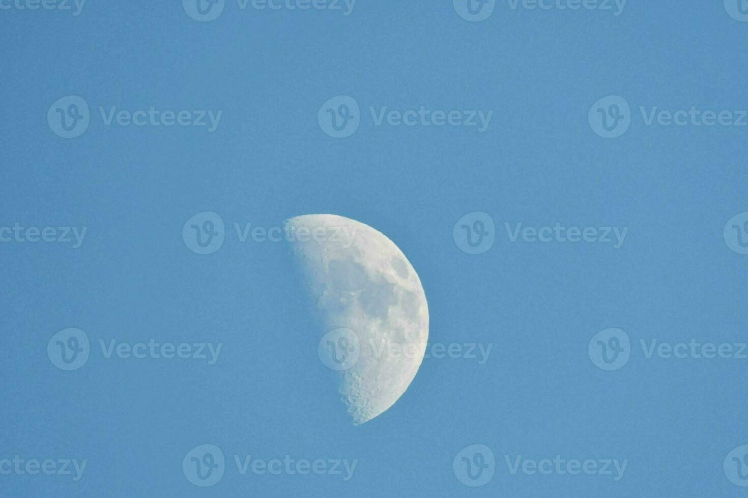 the moon is seen in a clear blue sky photo