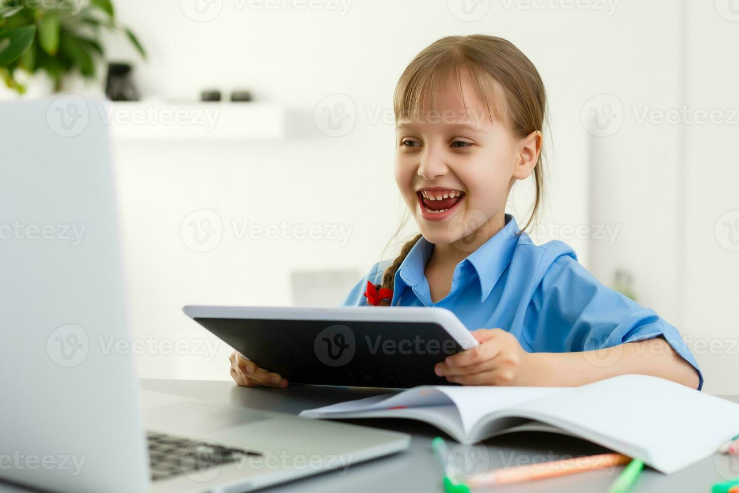 Remote lessons. The child smiles happily and gets knowledge remotely. Little girl study online learning from home. Online school. photo