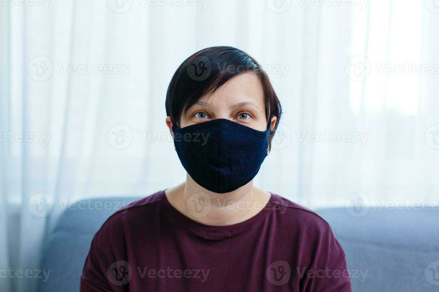 Close up woman portrait, Young woman wearing home made hygienic face medical mask to prevent infection, illness or flu and 2019-nCoV. Black background. Protection against disease, coronavirus. photo