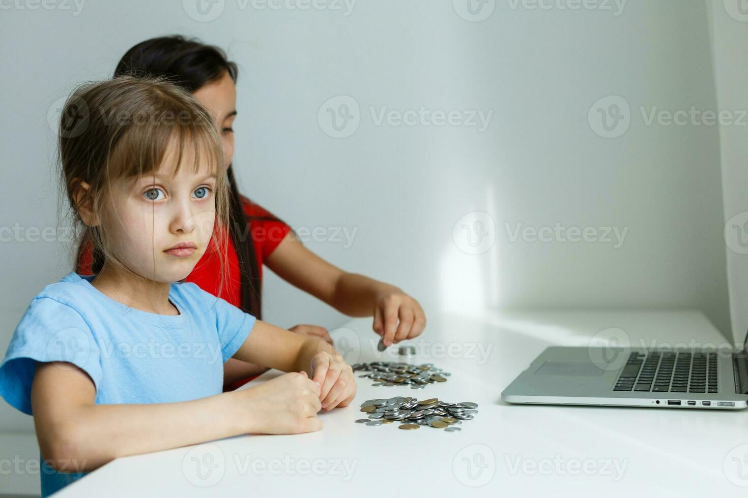 portrait of little girls sitting at table and calculating money photo