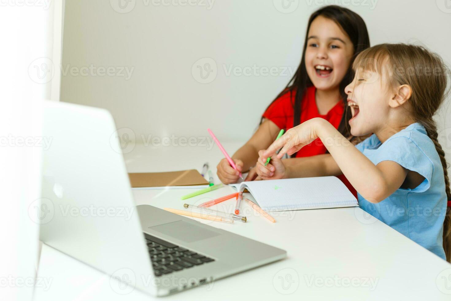 Cool online school. Kids studying online at home using a laptop. Cheerful young little girls using laptop computer studying through online e-learning system. Distance or remote learning photo