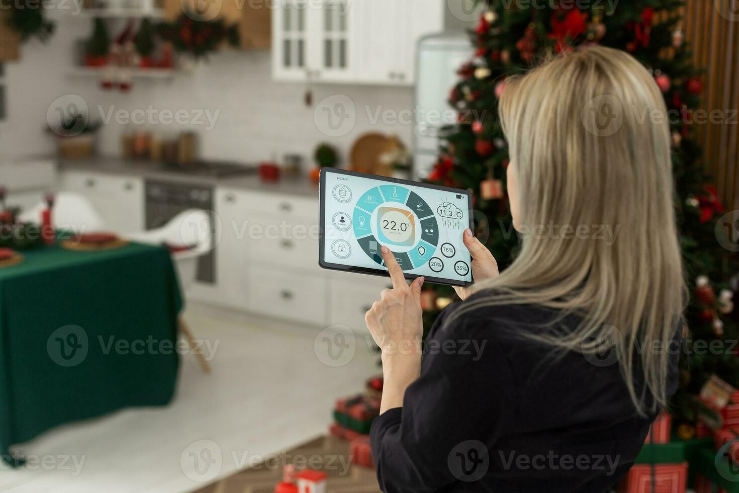 Woman pushing button on kitchen app of smart home on digital tablet at home. Concept of modern home control. Idea of domestic lifestyle. Cropped image of girl. Blurred man on background using laptop. photo