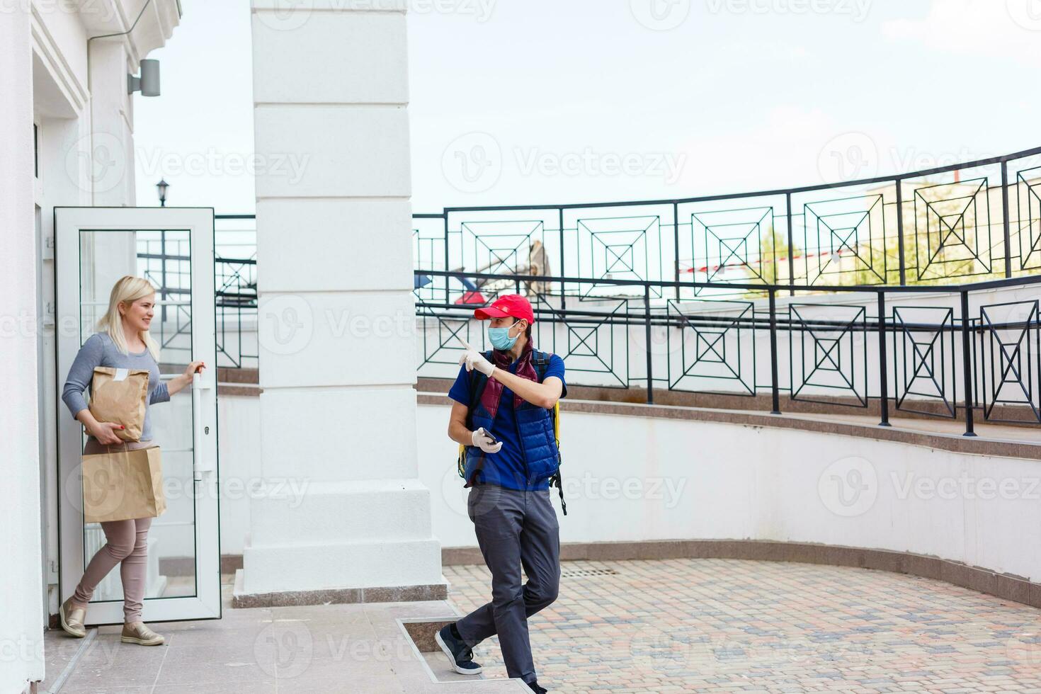 delivery man with thermo backpack and smiling woman in office photo