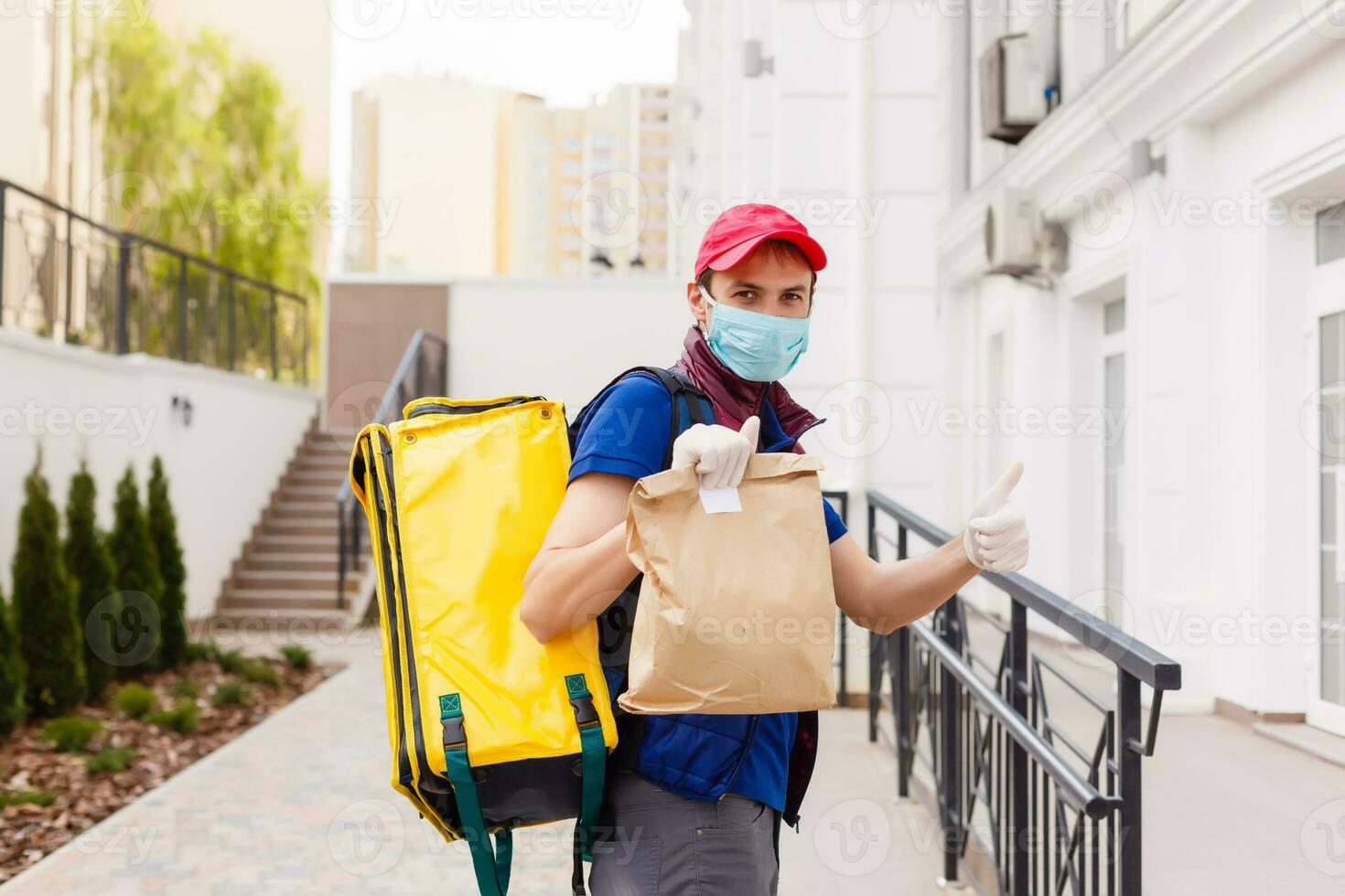 Delivery Man standing with yellow thermo backpack for food delivery near the entrance home with empty space to copy paste photo