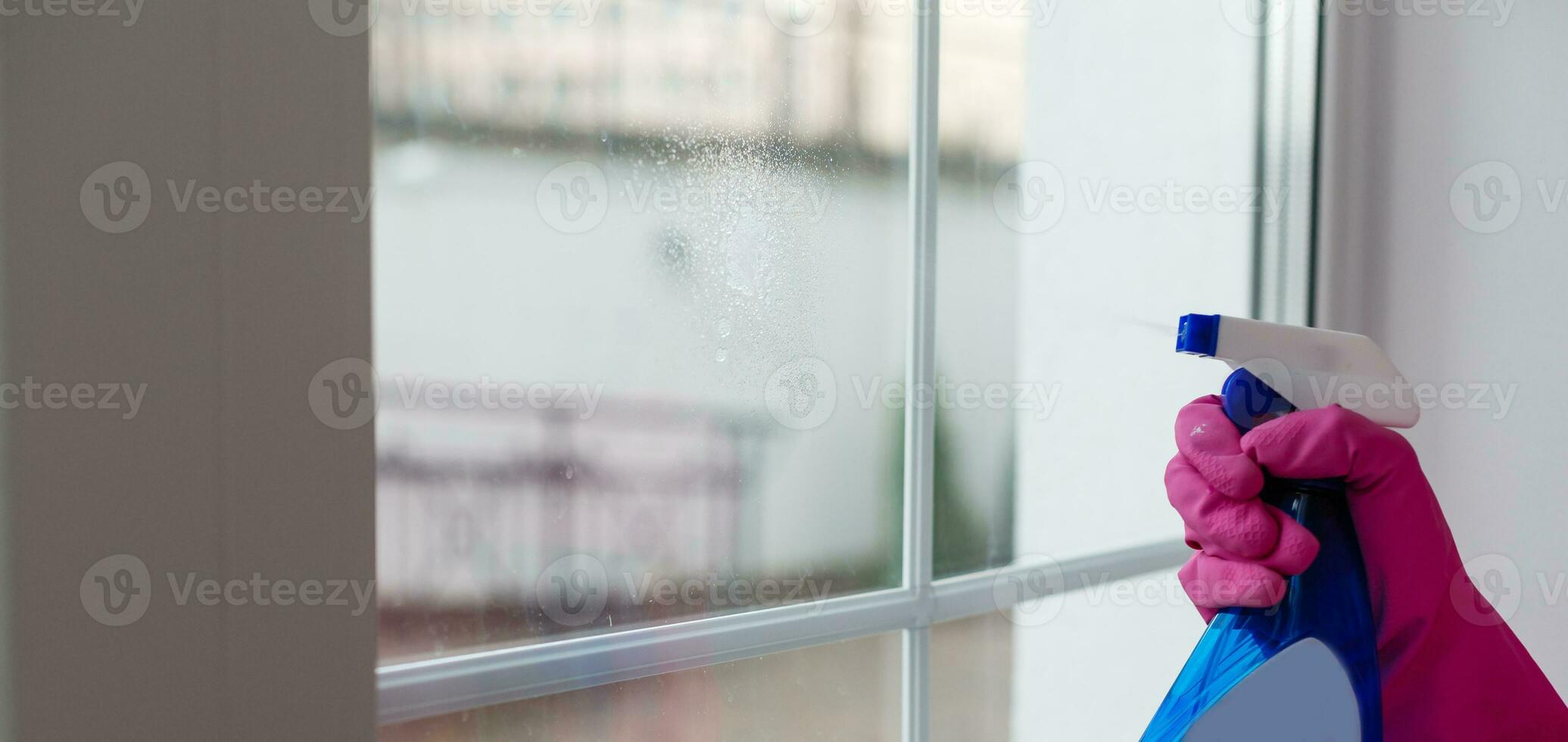 Woman cleaning a window with cleaning sprayer. photo