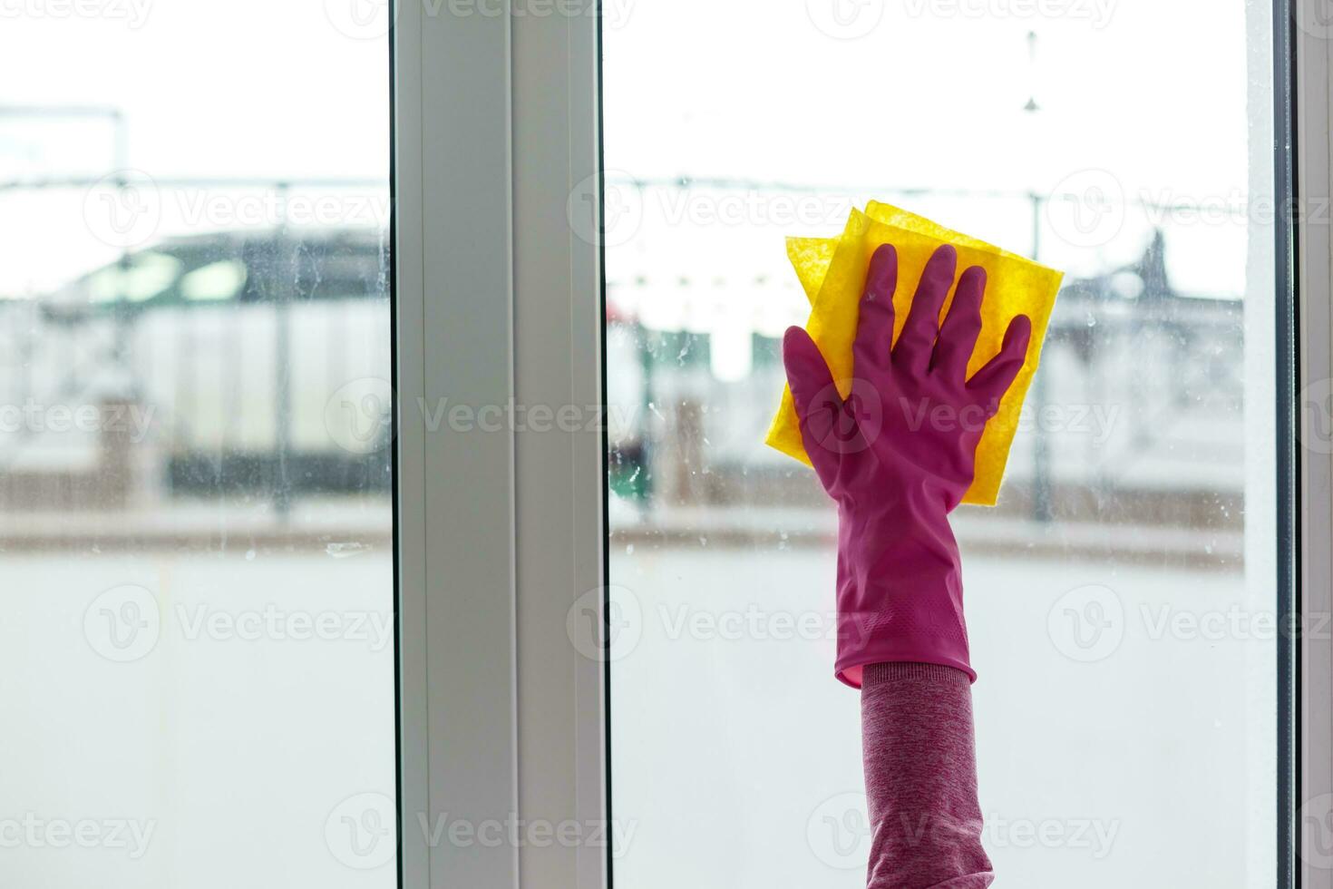 mujer limpieza un ventana con limpieza pulverizador. foto