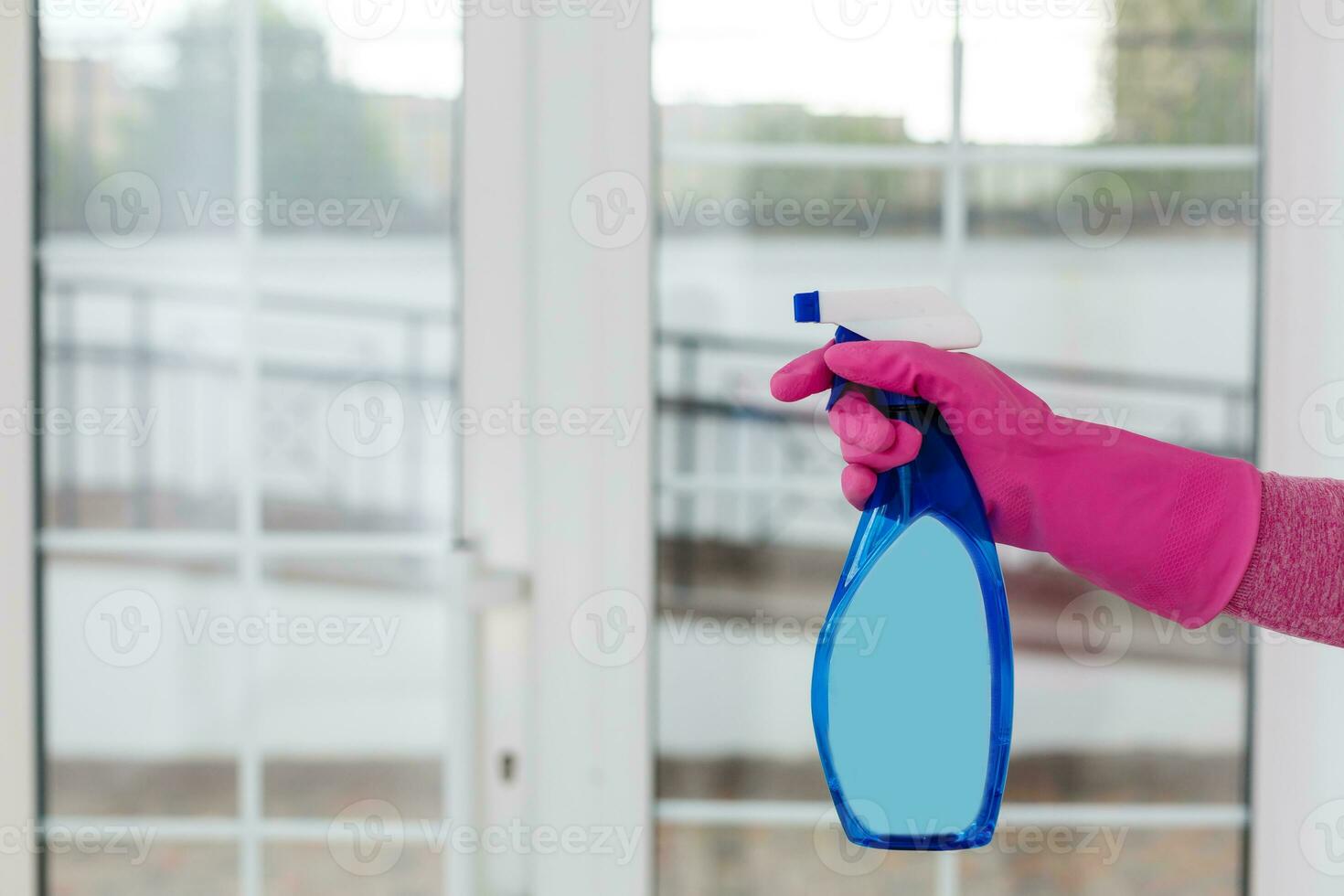 Woman cleaning a window with cleaning sprayer. photo