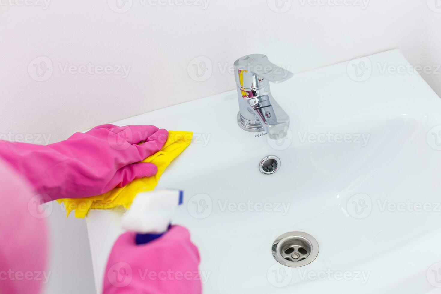 Hand with sponge cleaning white sink. photo