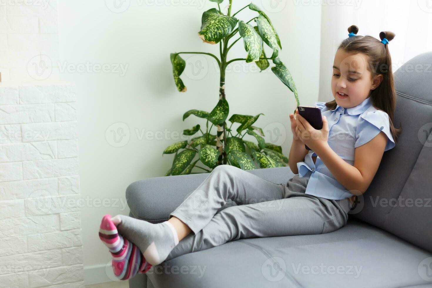 children, technology and communication concept - smiling girl texting on smartphone and lying in bed at home photo
