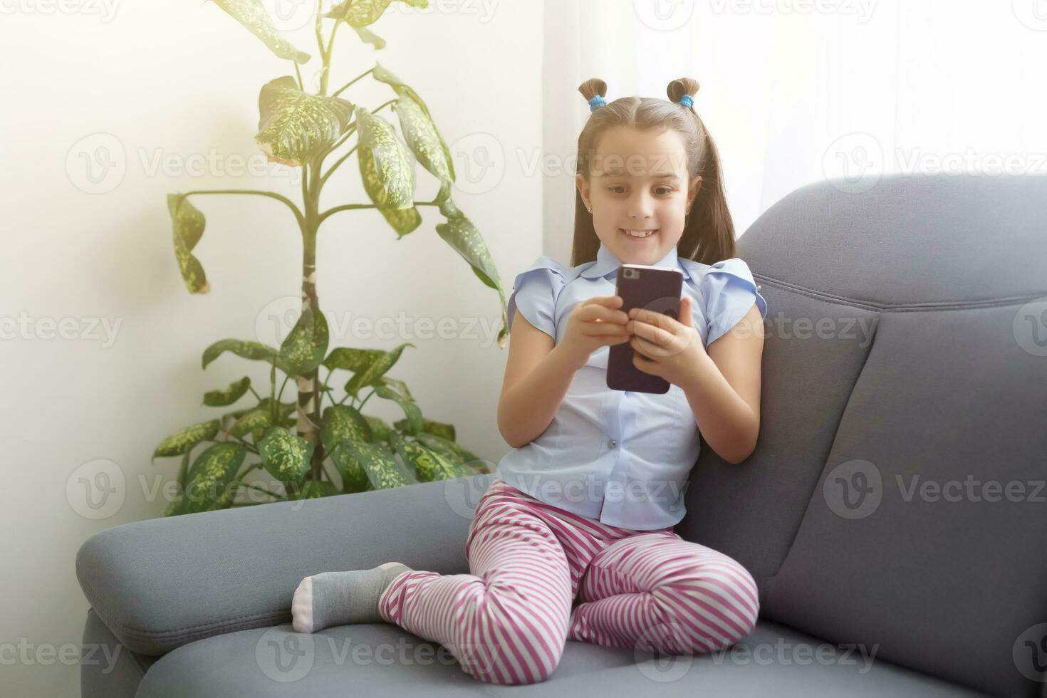 children, technology and communication concept - smiling girl texting on smartphone and lying in bed at home photo