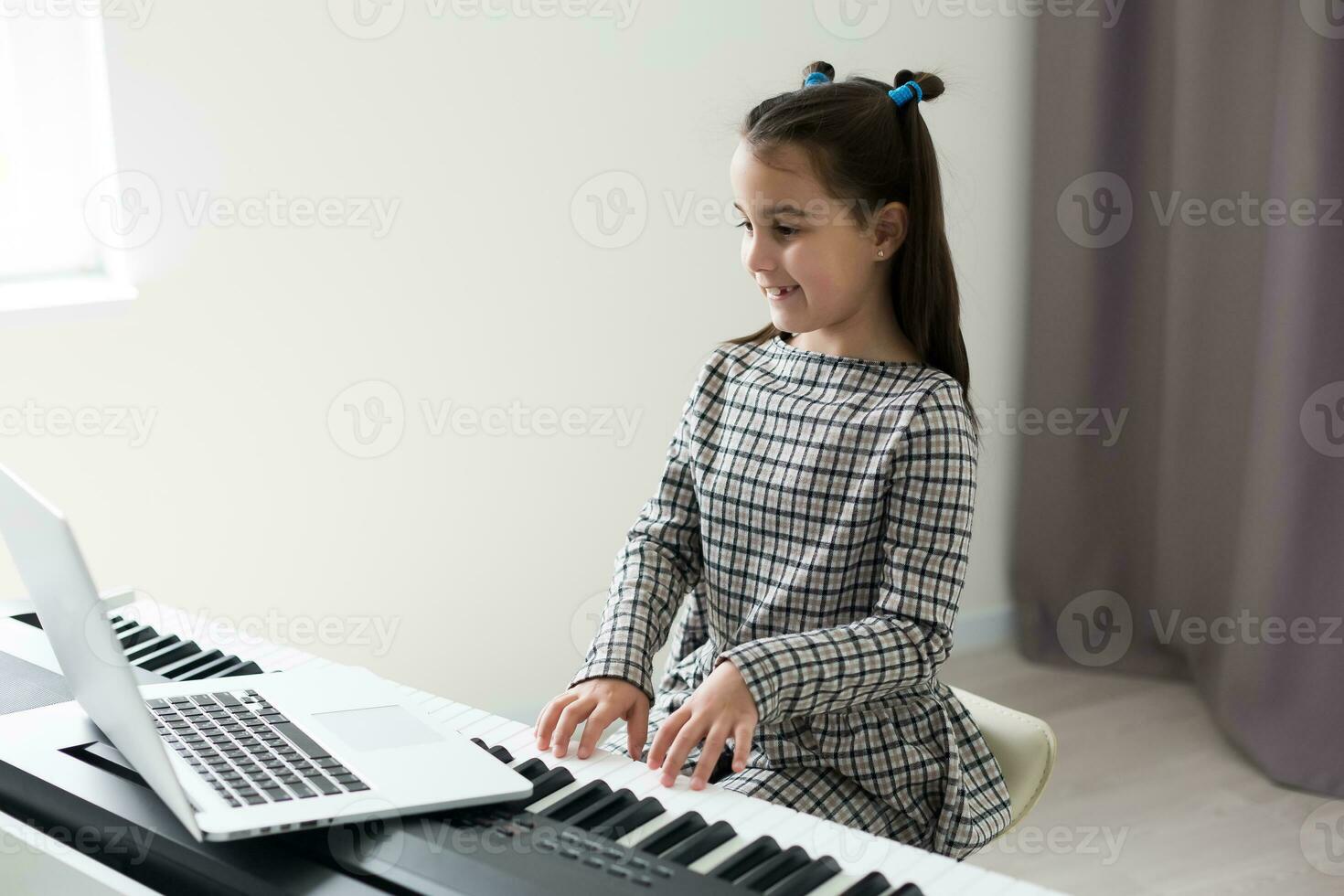 Little girl distance learning the piano online during quarantine. Coronavirus concept. photo