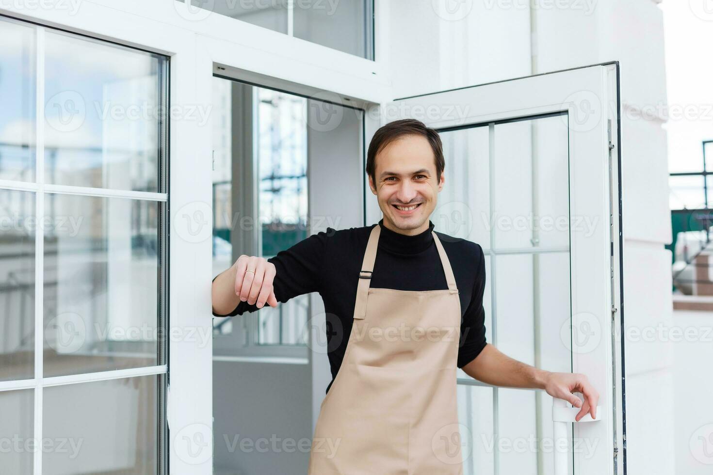 Portrait of a waiter showing open sign at the coffee shop photo