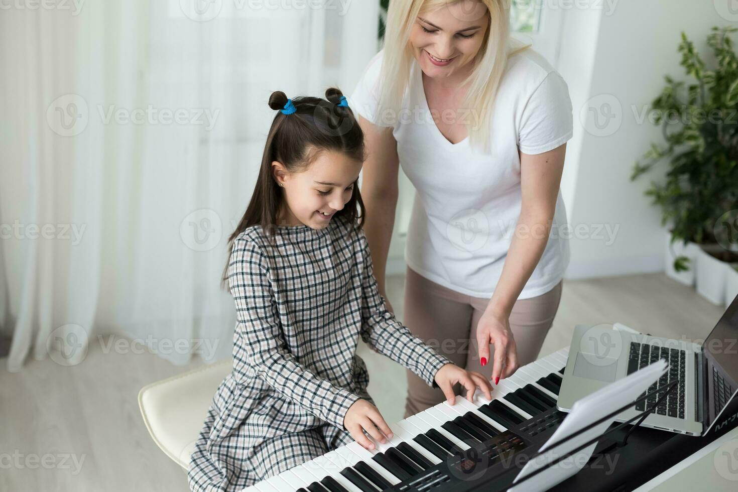 Woman helping her daughter to play the piano, body and buttons of the piano were digitally modified photo