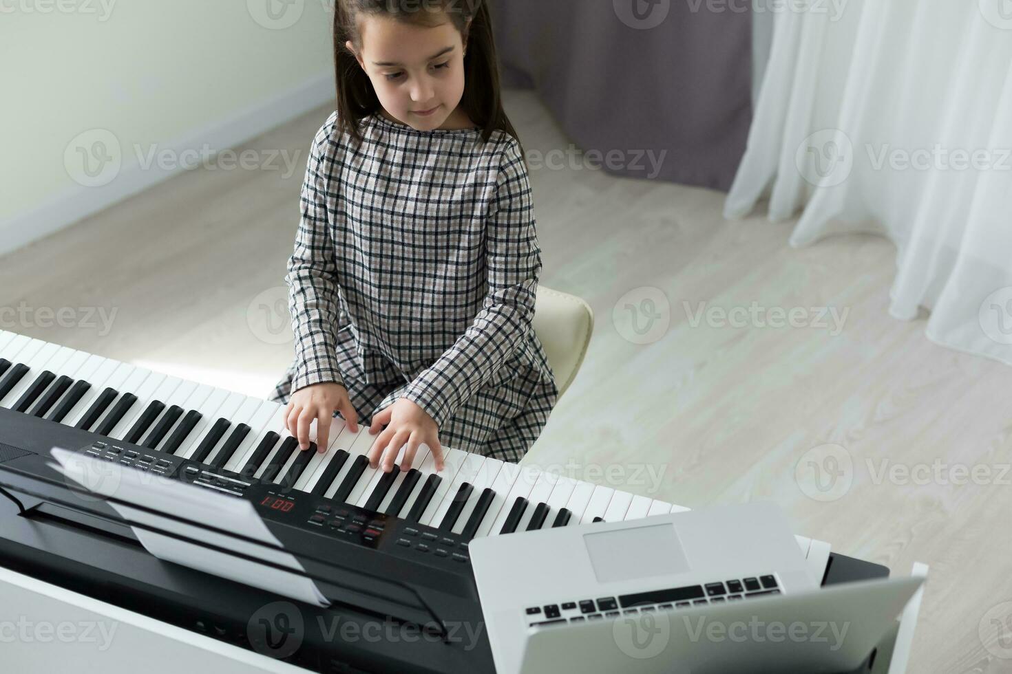 Home lesson on music for the girl on the piano. The idea of activities for the child at home during quarantine. Music concept photo