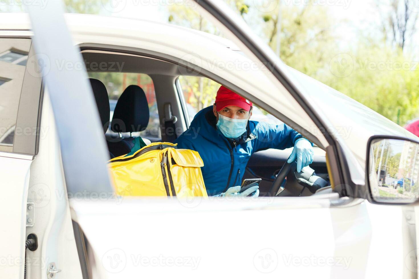 food delivery man in a protective mask and gloves with a thermo backpack near a house during the quarantine period photo