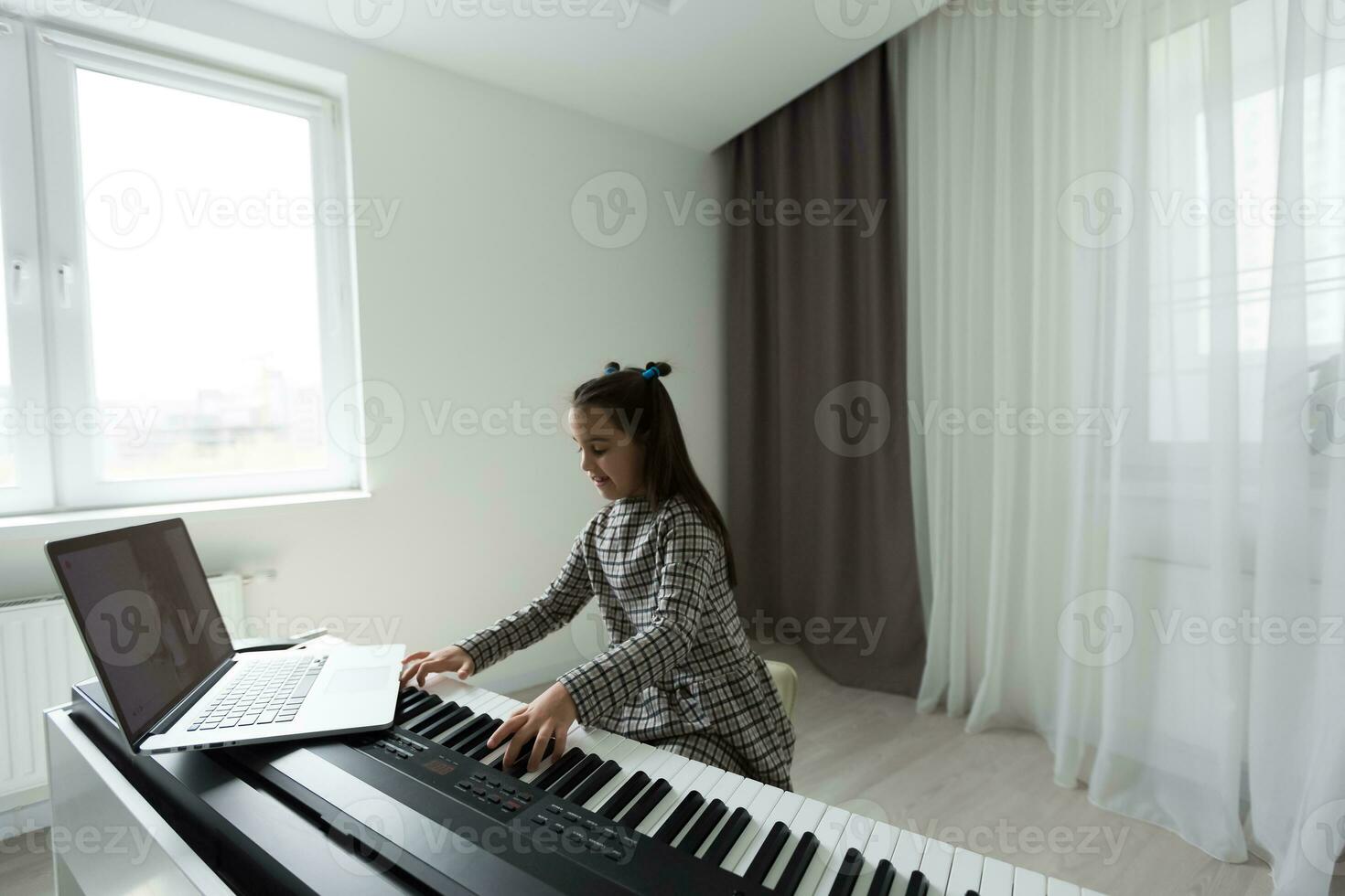 Home lesson on music for the girl on the piano. The idea of activities for the child at home during quarantine. Music concept photo