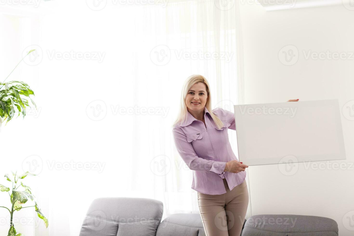 woman holds photo canvas at home