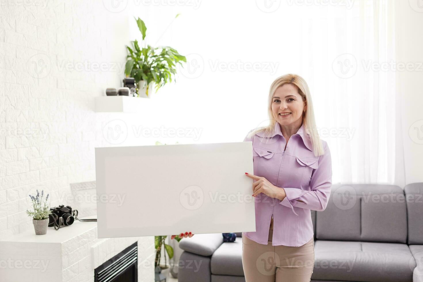 Happy european girl holding a blank canvas in her hands. Empty frame for text or photo. Young woman with mockup poster photo