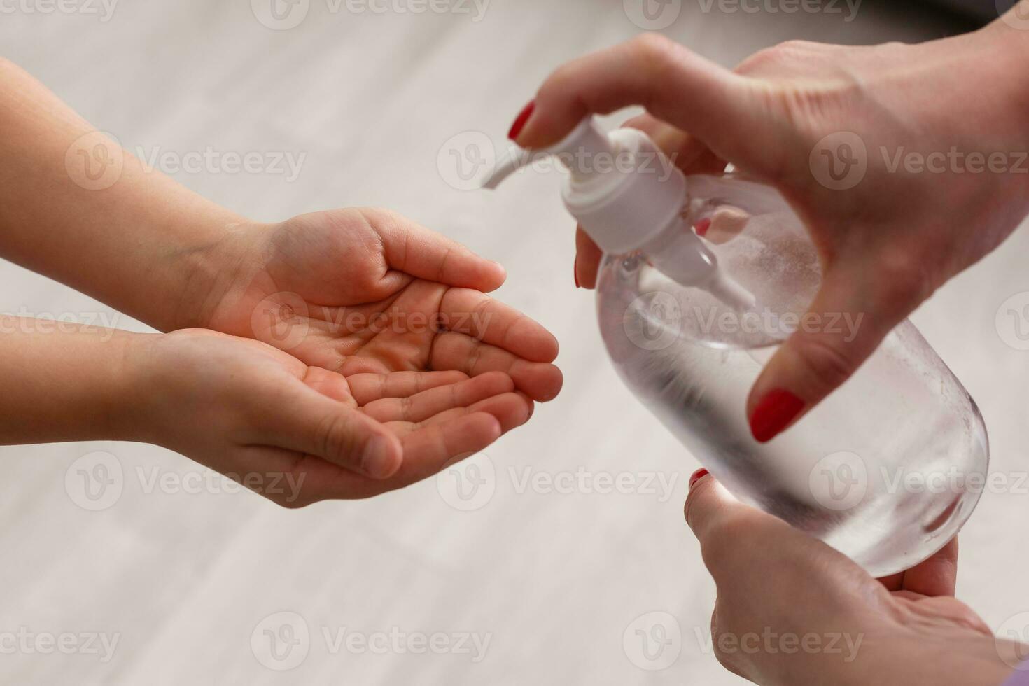 mujer utilizando alcohol rociar a pequeño niño muchacha. madre y hija utilizando lavar mano desinfectante gel. proteccion gérmenes en manos covid-19 brote. coronavirus, contaminación proteccion concepto. permanecer a hogar. foto