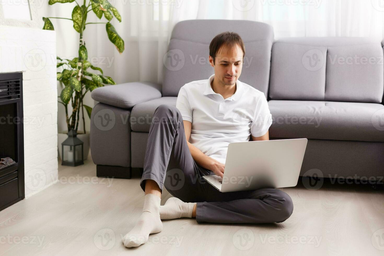 Happy smiling young man watching and working on computer laptop at home photo