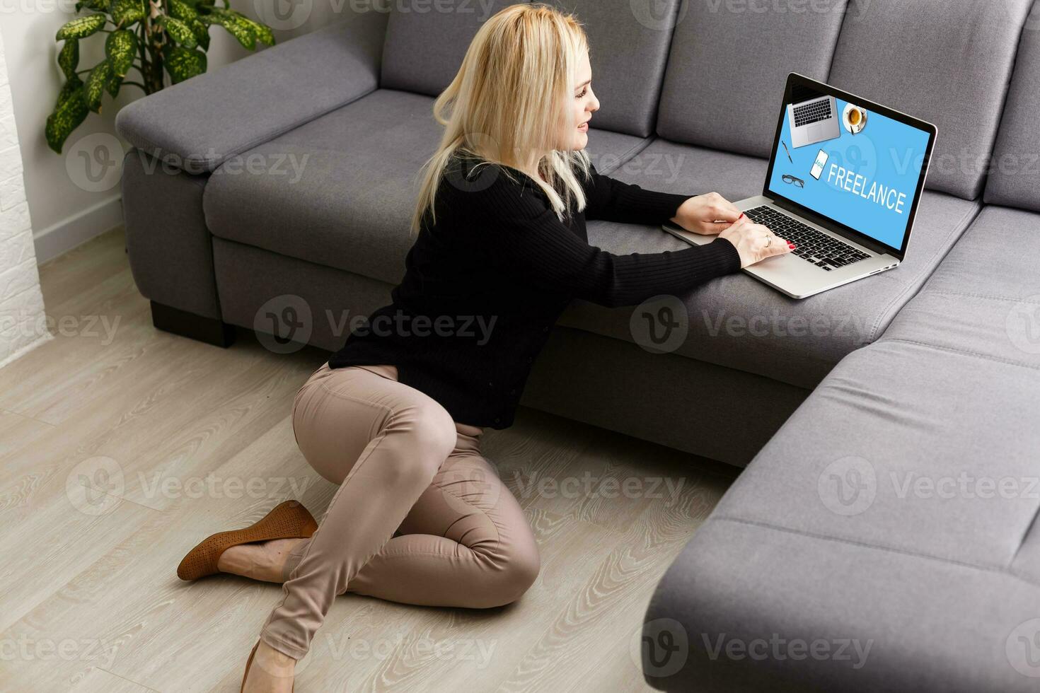 Young female entrepreneur working sitting on the floor typing on her laptop computer at home office photo