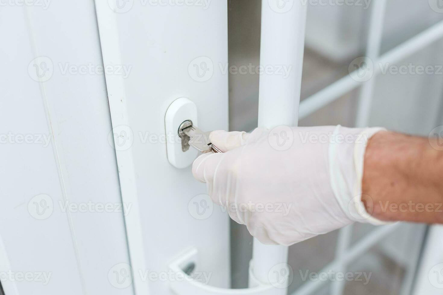 closeup of a caucasian man opening a door with a key wearing latex gloves, Hygiene concept. photo