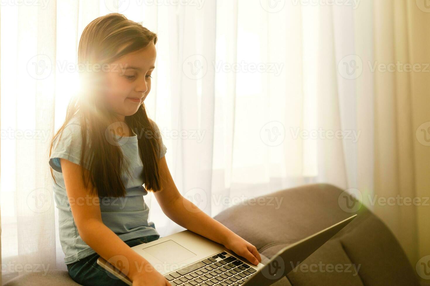 Head shot close up portrait of happy small pupil learning at home. Smiling little child girl enjoying doing lessons in living room. Smart kid schoolgirl looking at camera, studying remotely online. photo