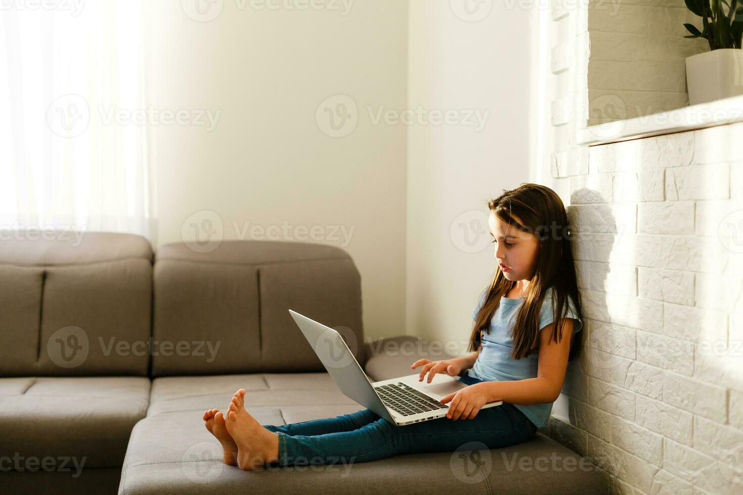 Remote lessons. The child smiles happily and gets knowledge remotely. Little girl study online learning from home with laptop. Online school. photo