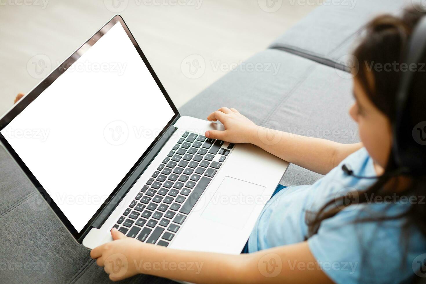 Head shot close up portrait of happy small pupil learning at home. Smiling little child girl enjoying doing lessons in living room. Smart kid schoolgirl looking at camera, studying remotely online. photo