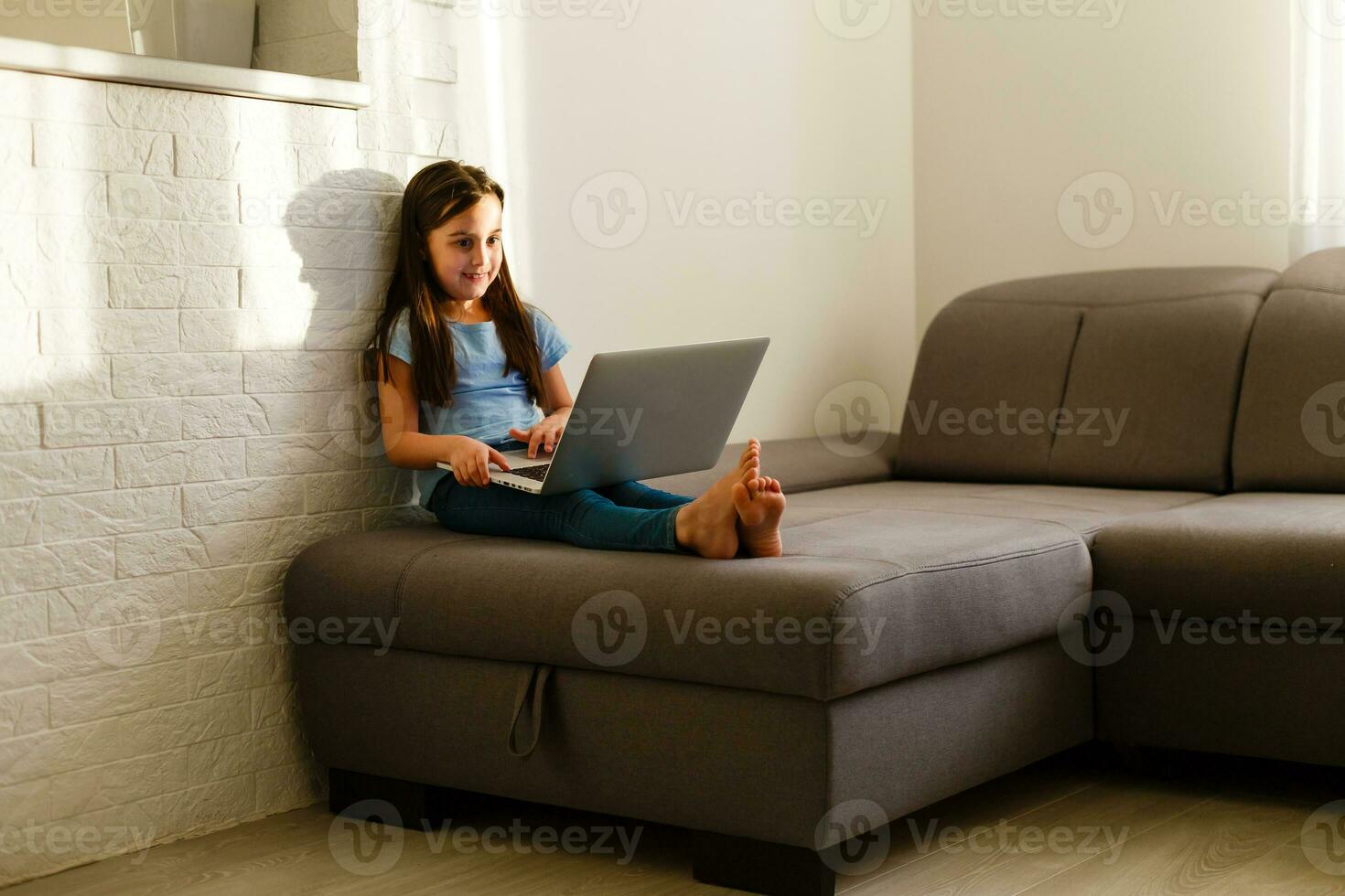 Remote lessons. The child smiles happily and gets knowledge remotely. Little girl study online learning from home with laptop. Online school. photo