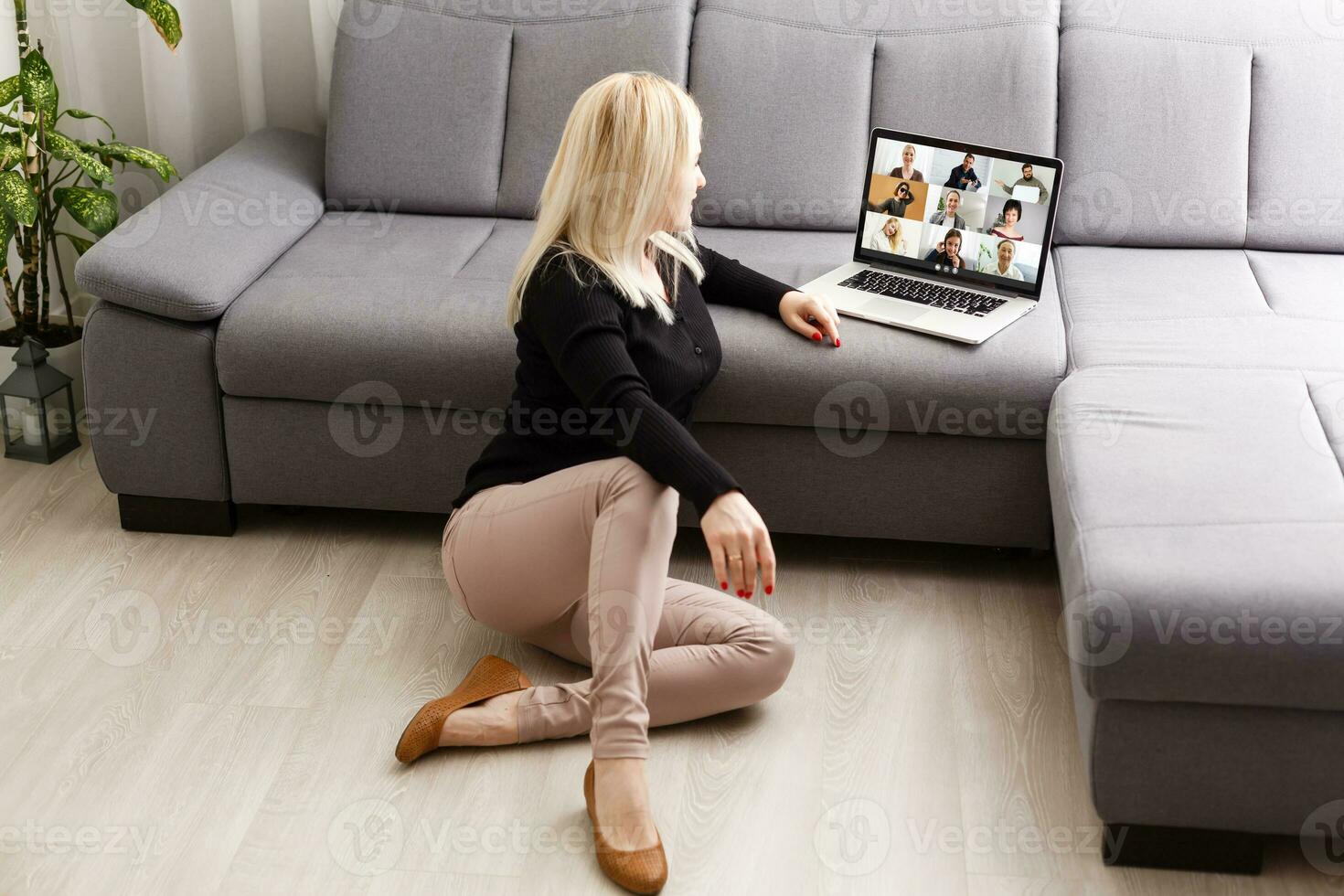 Happy casual beautiful woman working on a laptop sitting on the floor in the house. photo